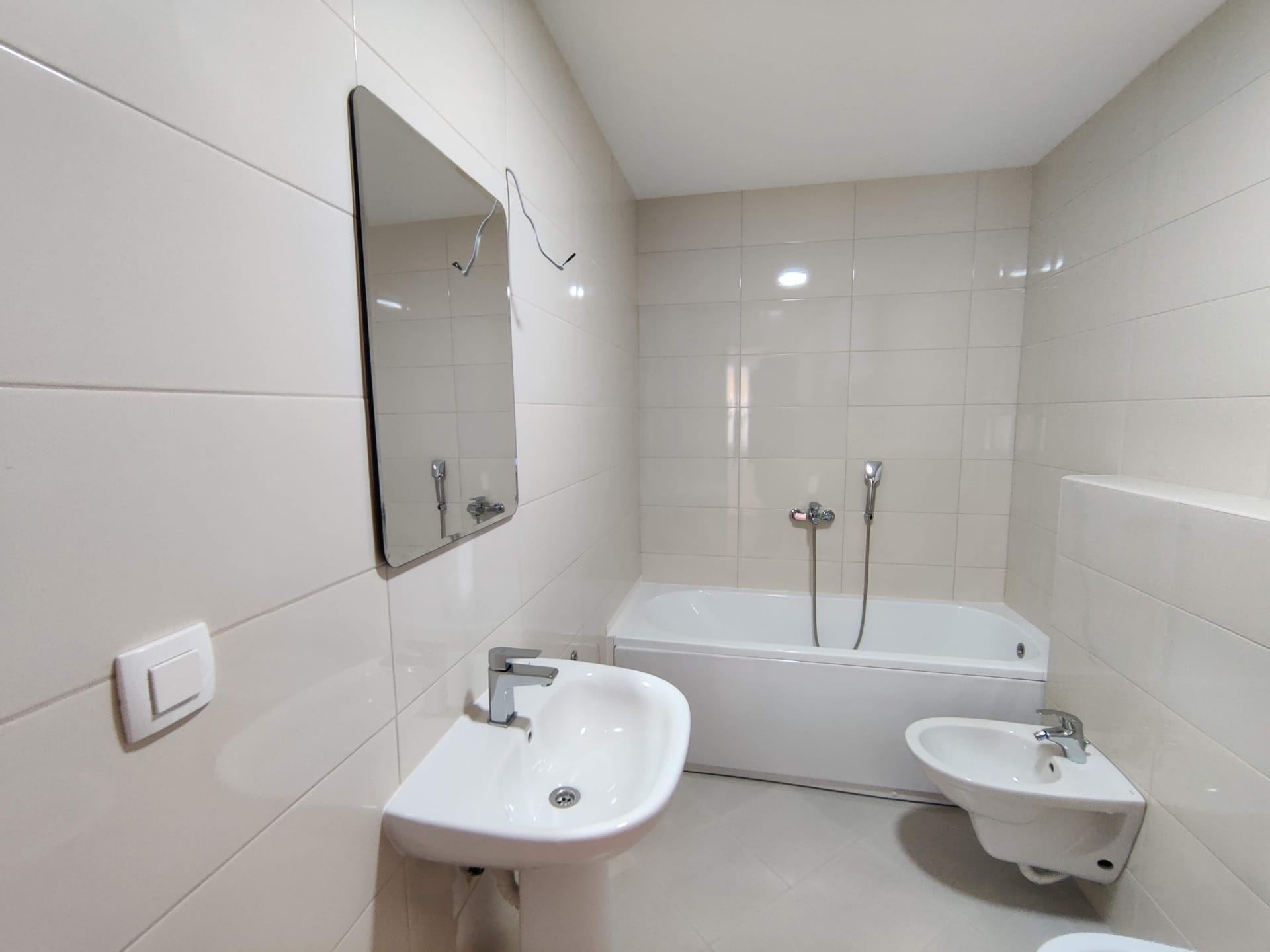 Salle de bain lumineuse avec baignoire et bidet dans un appartement, Bečići, Monténégro : finition moderne en carrelage et équipements sanitaires.