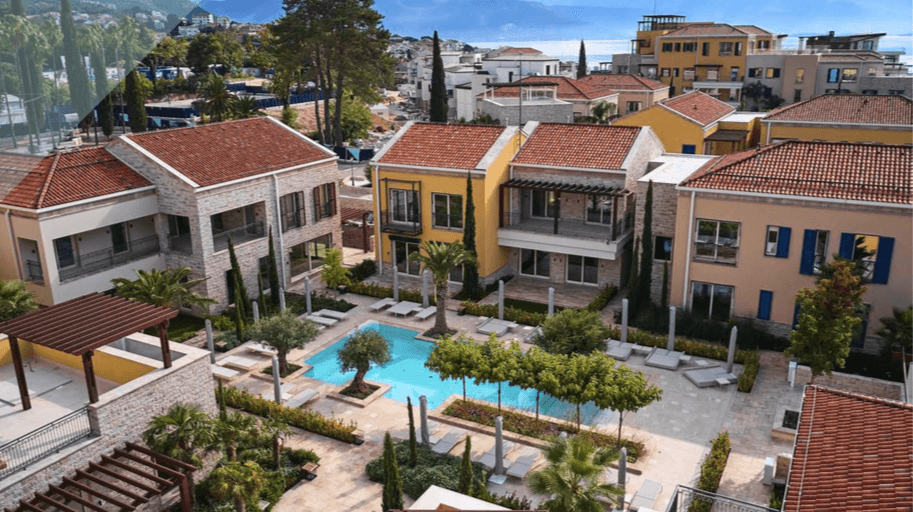 Aerial view of the Porto Novi residential complex in Kumbor, Montenegro: villas with tiled roofs and a shared swimming pool with a terrace.