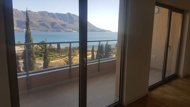 Pogled iz dnevne sobe stana u Bečićima, Crna Gora: panoramski prozori, terasa s pogledom na more i planine.