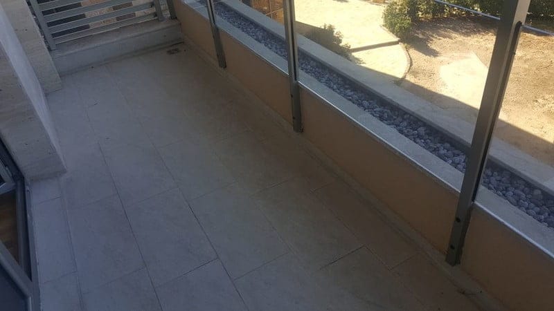 Prostran balkon sa kamenim oblogama i staklenom ogradom u modernom stanu, Bečići, Crna Gora.