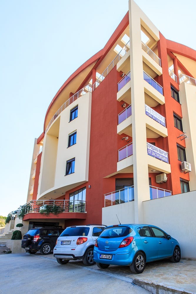Moderner Wohnkomplex in Dobra Voda, Montenegro: Gebäudefassade mit Balkonen und Parkplatz am Haus.