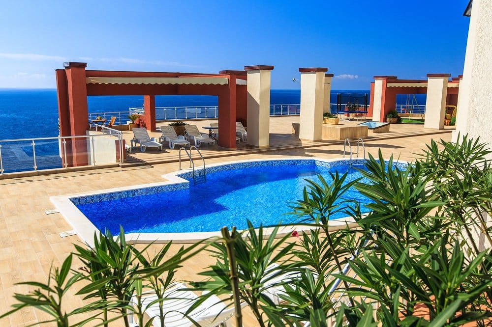 Offener Pool mit Meerblick in einer Wohnanlage, Dobri Vody, Montenegro: Terrasse mit Liegestühlen und Ruhebereich.