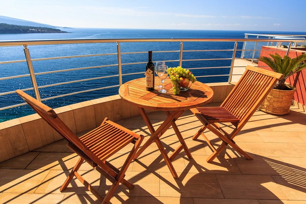 Balkon mit Holzmöbeln und Panoramablick auf das Meer in einer Wohnanlage in Dobra Voda, Montenegro.
