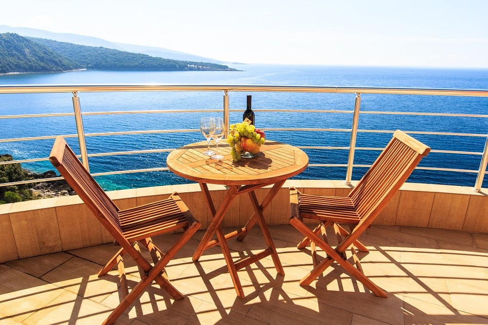 Balkon mit Holzmöbeln und Panoramablick auf das Meer in einer Wohnanlage, Dobra Voda, Montenegro.
