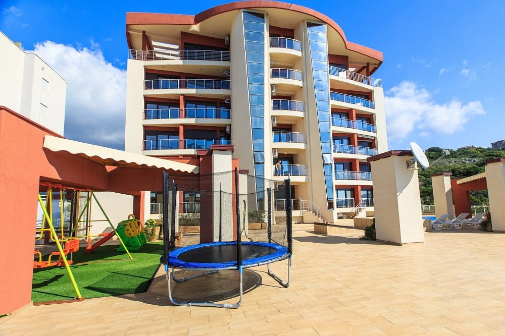 Moderner Wohnkomplex mit Spielplatz und Pool in Dobra Voda, Montenegro: Blick auf die Gebäudefassade.