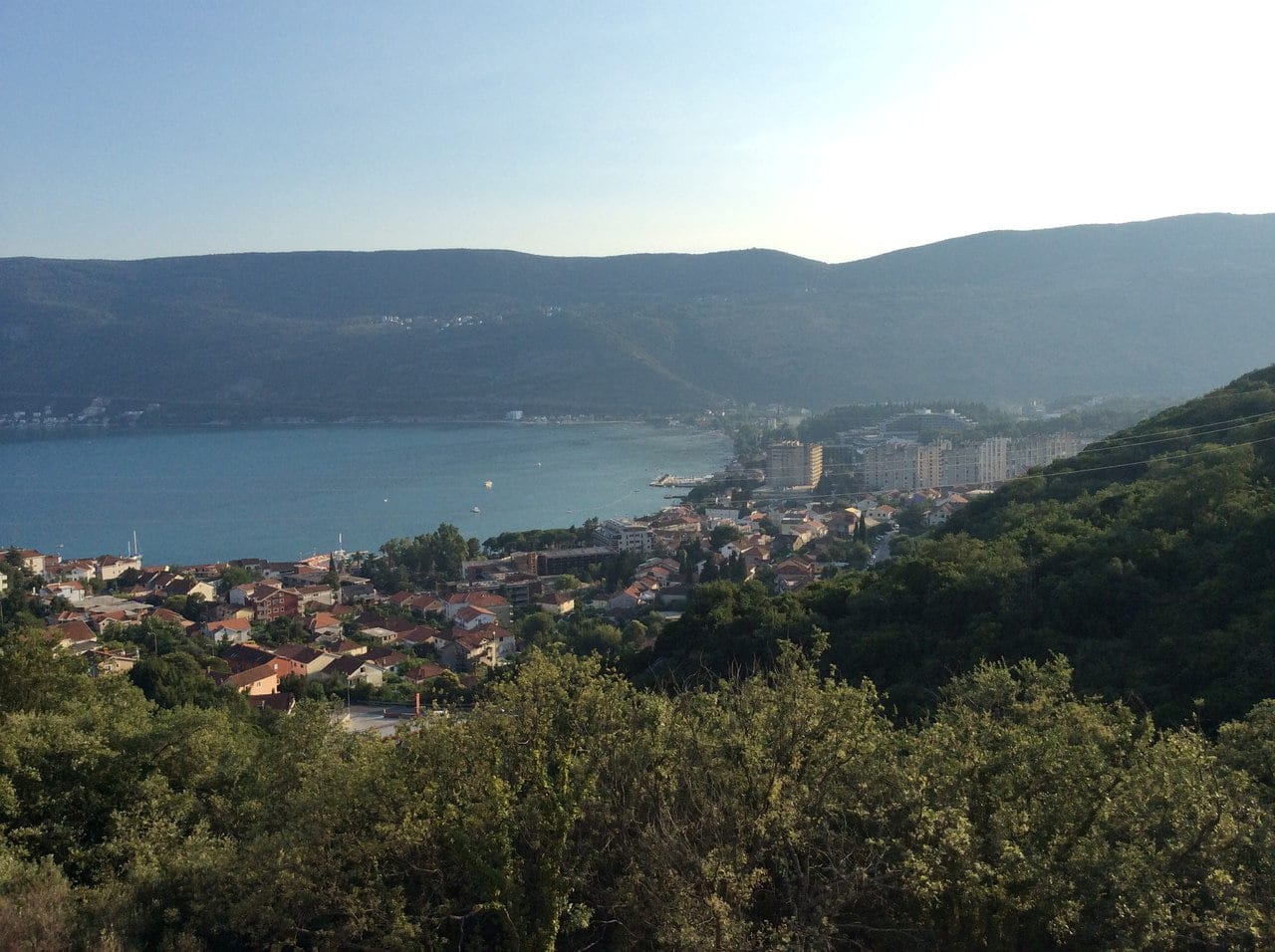 Panoramski pogled na grad Herceg Novi i Bokokotorski zaliv, Crna Gora: morski pejzaž sa planinama i stambenom izgradnjom.