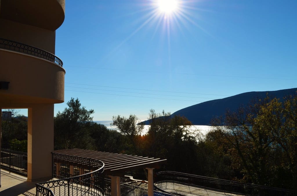 Panoramski pogled na more i planine sa terase stana u Herceg Novom, Crna Gora, sa kovanom ogradom i pergolom.