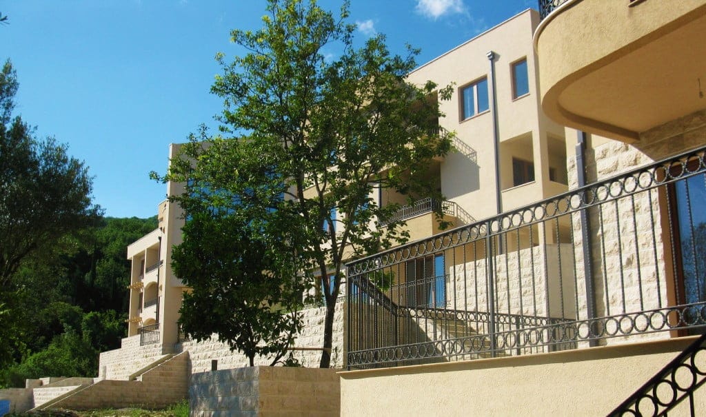 Savremena stambena kuća sa kamenim oblogama fasade i terasama u Herceg Novom, Crna Gora, okružena zelenilom.