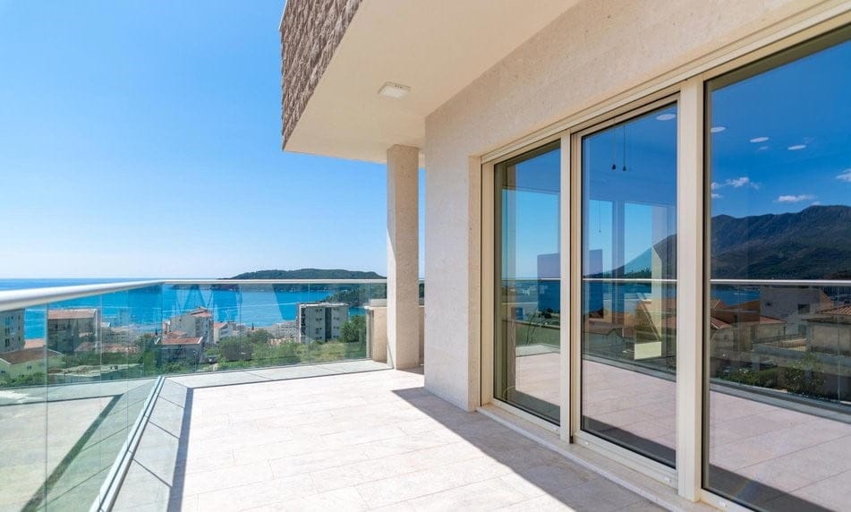 Deniz ve dağların panoramik manzarasına sahip geniş teras, villa, Bečići, Karadağ. Modern kaplama ve cam korkuluklar.