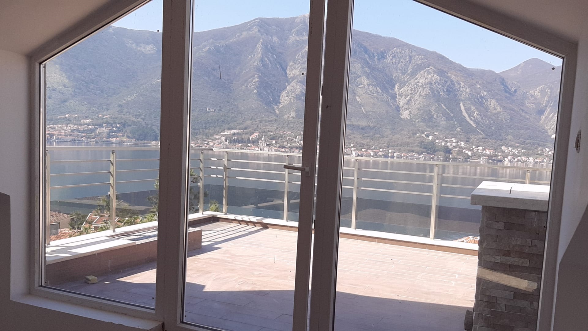 Blick von der Terrasse der Wohnung in Dobrota, Montenegro: Panorama der Bucht von Kotor und der Berge durch Glastüren.