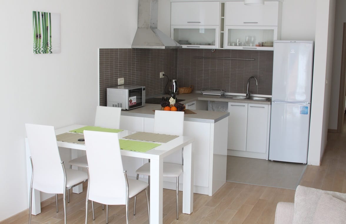 Moderne Küche mit hellen Möbeln und Essbereich in einer Wohnung in Dobrota, Montenegro. Gemütliches Interieur mit Geräten.