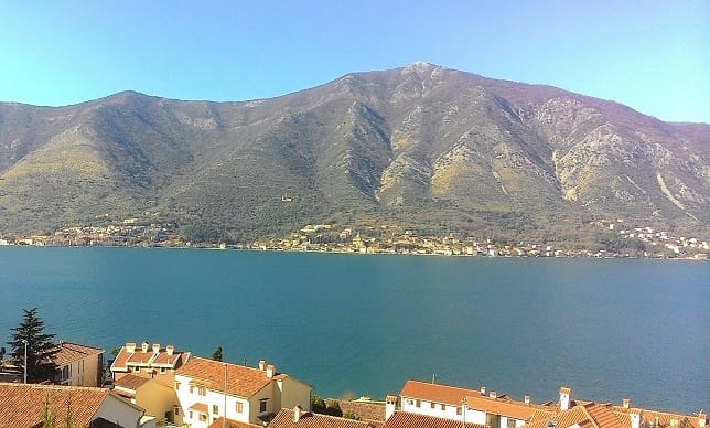 Panoramablick auf die Bucht von Kotor und die Berge aus einer Wohnung in Dobrota, Montenegro: im Vordergrund die Ziegeldächer der Häuser.