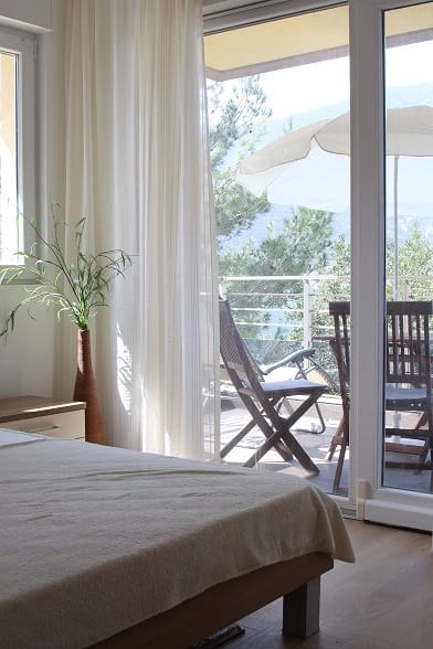 Schlafzimmer in einer Wohnung in Dobrota, Montenegro, mit Zugang zur Terrasse, Möbeln und Blick auf die Berge und das Meer.