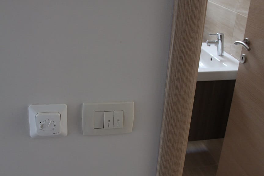 Thermostat der Fußbodenheizung und Lichtschalter in der Wohnung, Dobrota, Montenegro, Blick auf ein modernes Badezimmer.