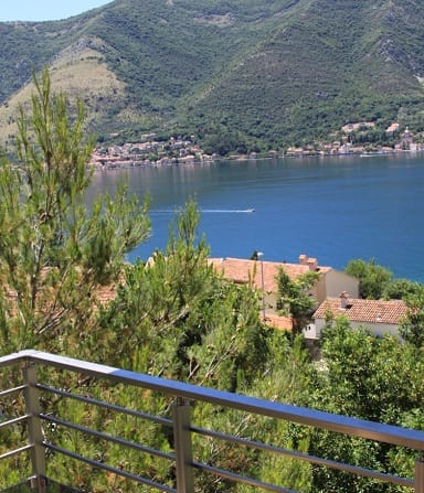Blick vom Balkon der Wohnung in Dobrota, Montenegro: Panorama der Bucht von Kotor, Berge und mediterrane Vegetation.