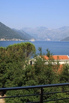 Blick vom Balkon der Wohnung in Dobrota, Montenegro: Panorama der Bucht von Kotor, Berge und grüne Bäume an der Küste.