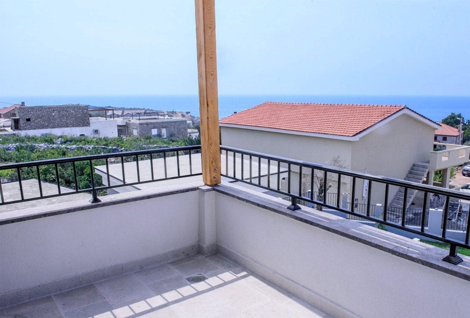 Otvorena terasa vile na Luštici, Crna Gora, sa panoramskim pogledom na more, kamenim podom i kovanom ogradom.