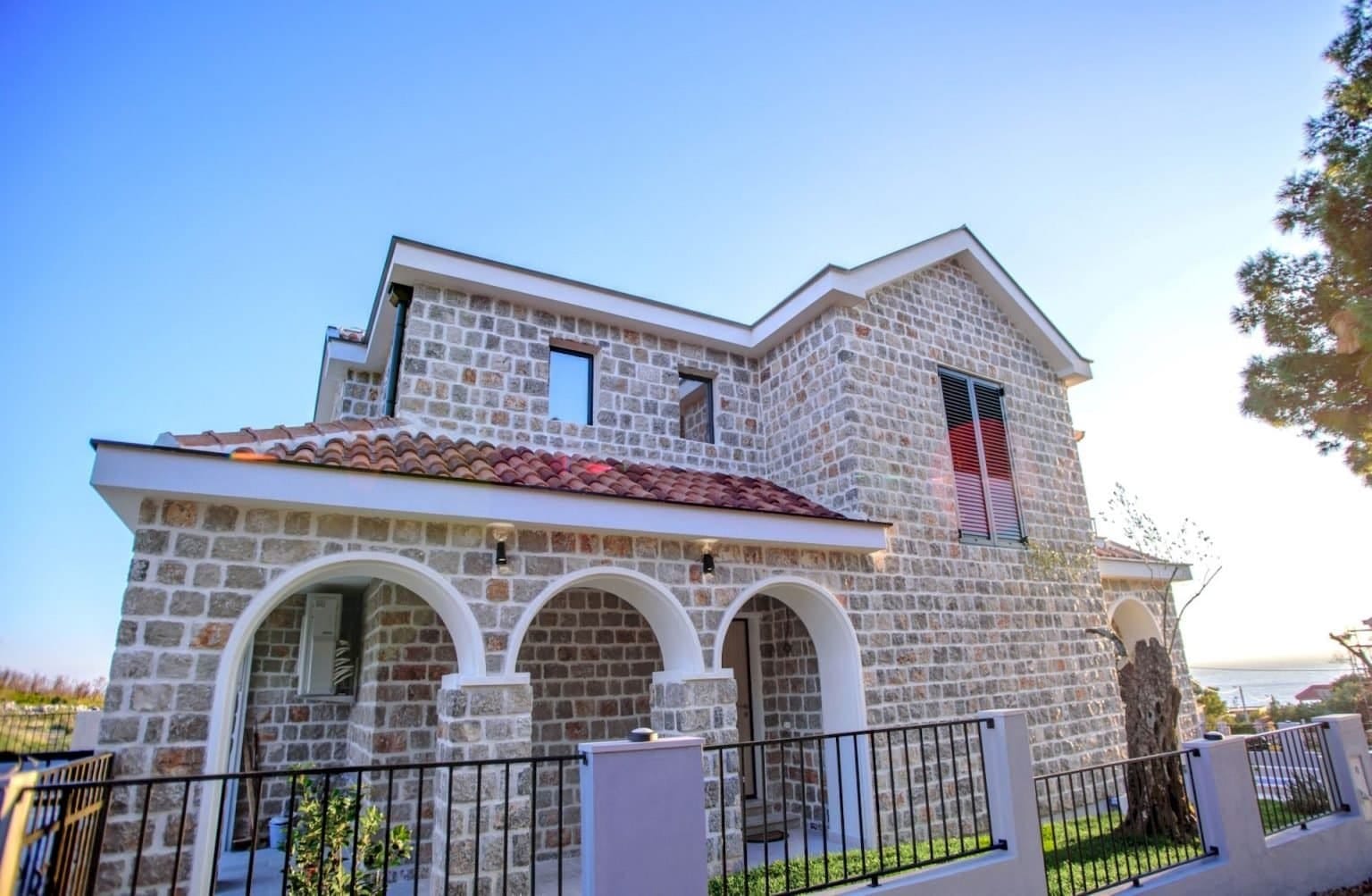 Dvospratna kamena vila sa lučnom terasom i krovom od crepa na poluostrvu Luštica, Crna Gora.