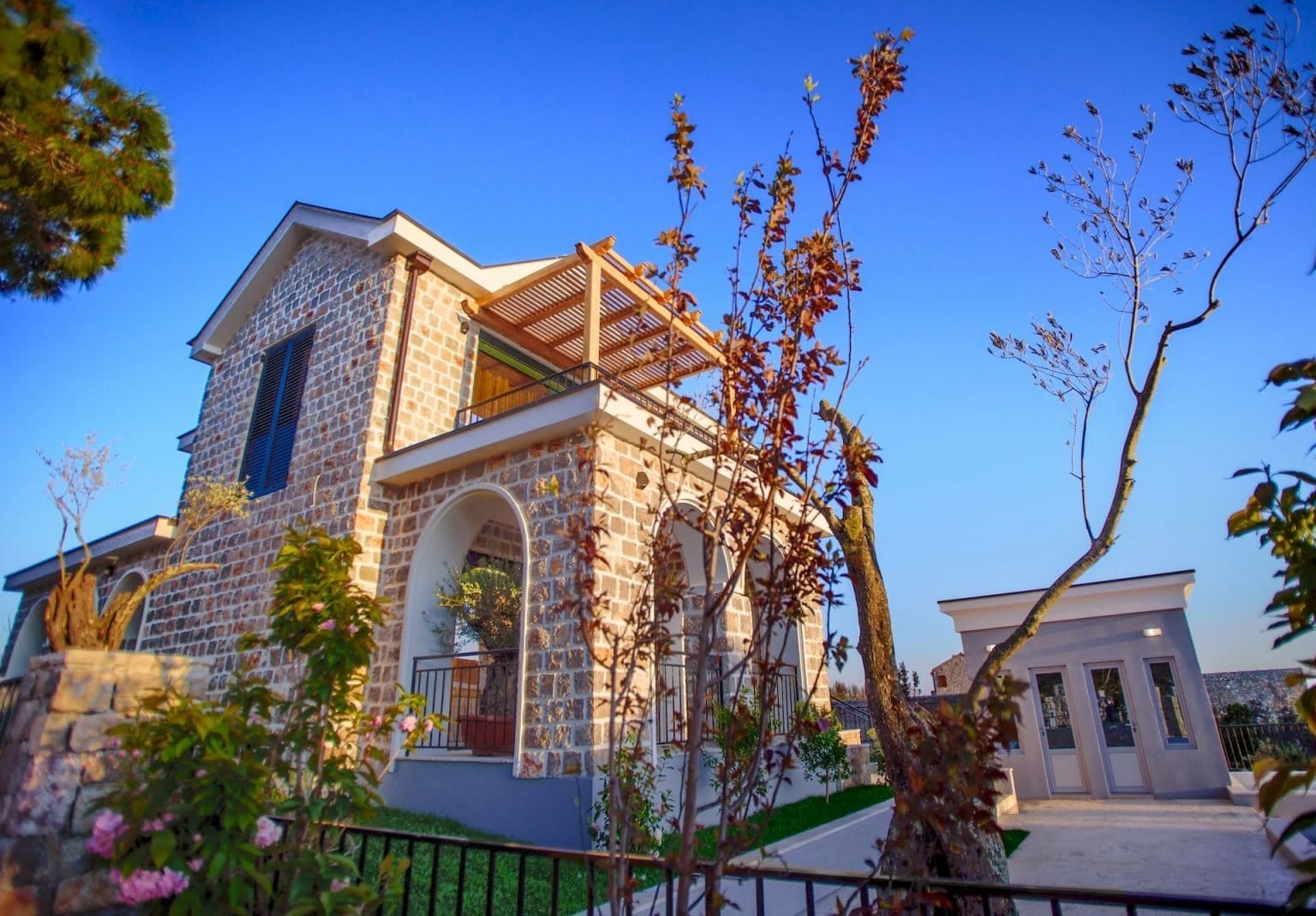 Dvospratna kamena vila u Luštici, Crna Gora, sa lučnom terasom, balkonom i uređenim placem.