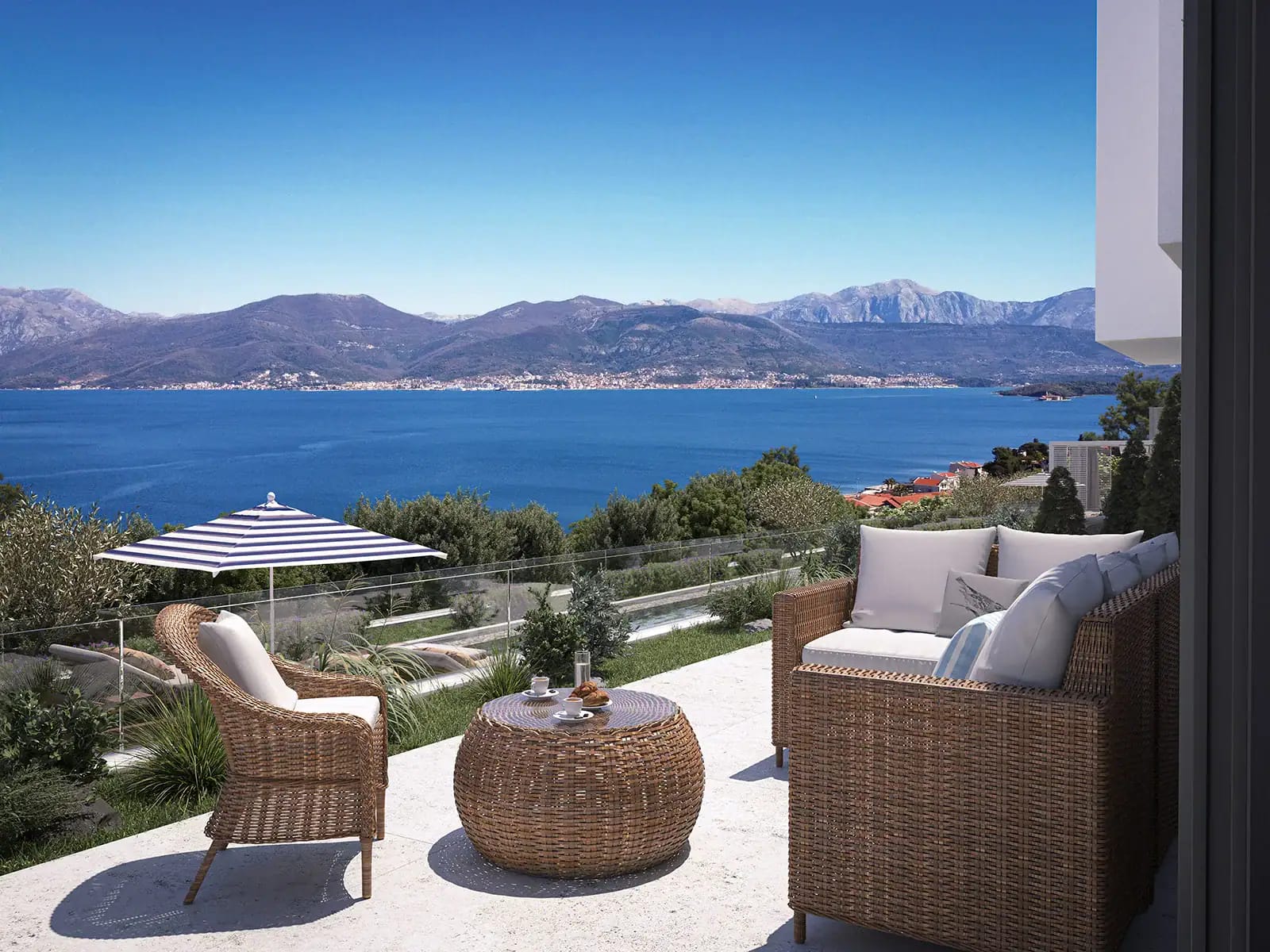 Terasa sa pletenim nameštajem i panoramskim pogledom na more i planine u stambenom kompleksu, Luštica, Crna Gora.