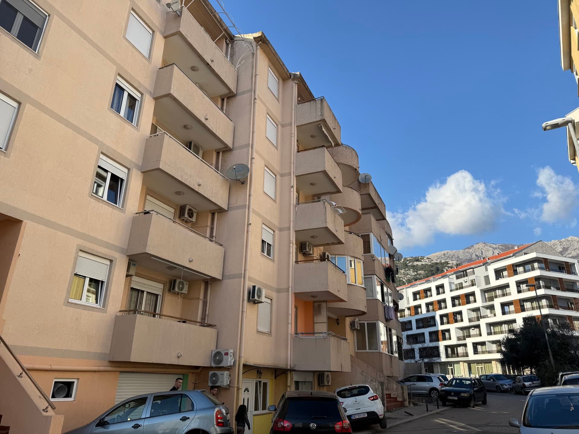 Facade of an apartment building with balconies and parking in Budva, Montenegro.