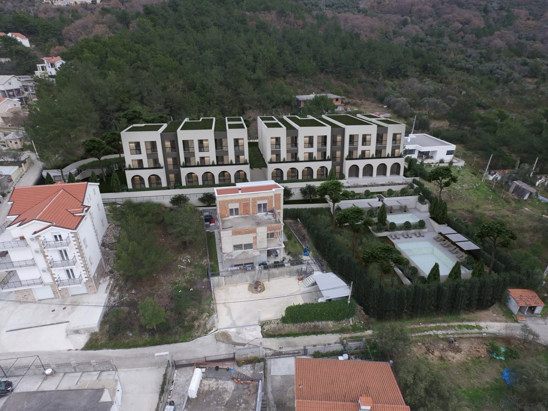 Pogled iz vazduha na stambeni kompleks u izgradnji sa bazenima u Kavaču, Crna Gora: moderne kuće okružene prirodom.