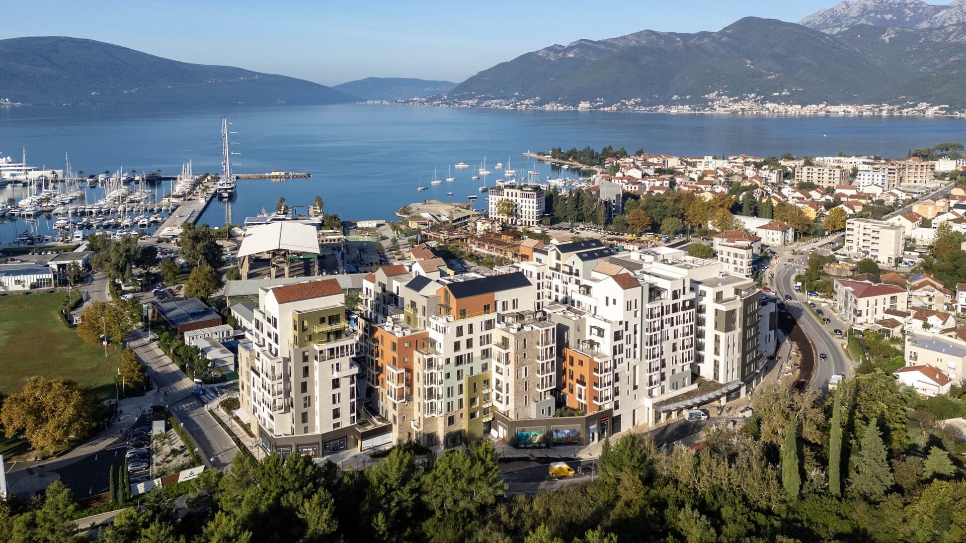 Pogled iz vazduha na stambeni kompleks u Porto Montenegru, Tivat, Crna Gora: moderne zgrade uz jahtenu marinu i more.