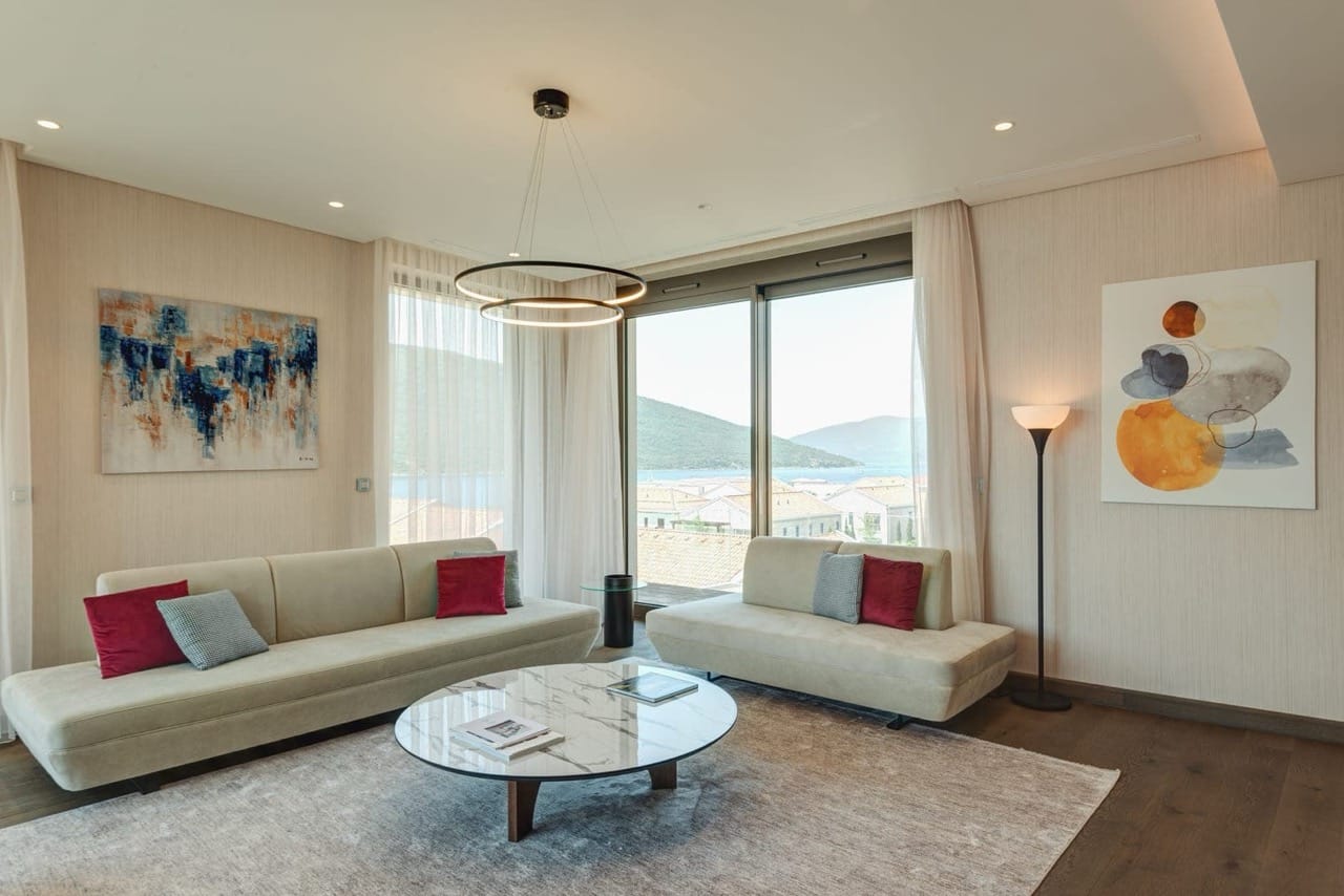 Modern living room in Portonovi, Kumbor, Montenegro: light furniture, marble table, and panoramic sea view.
