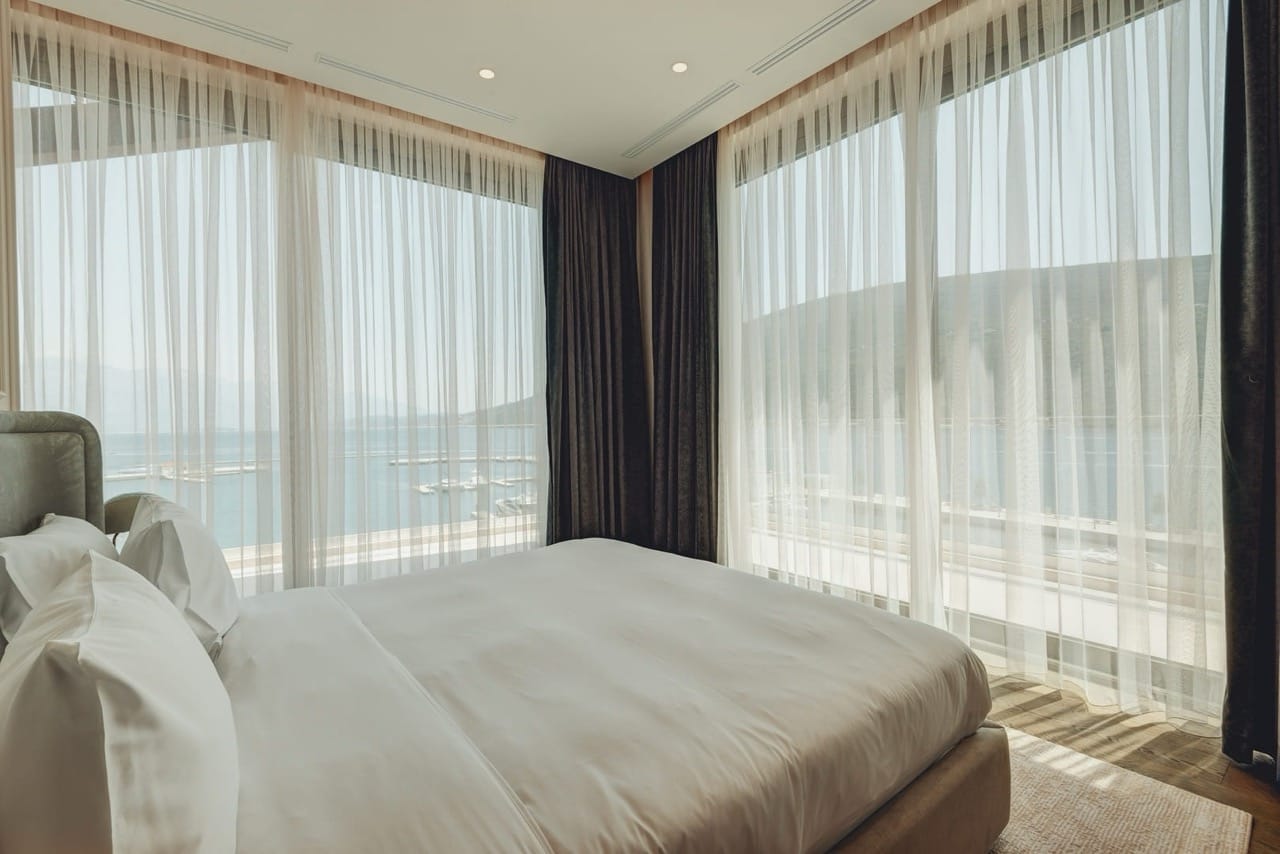 Bedroom in the Portonovi apartments, Kumbor, Montenegro: panoramic windows with sea and marina views.