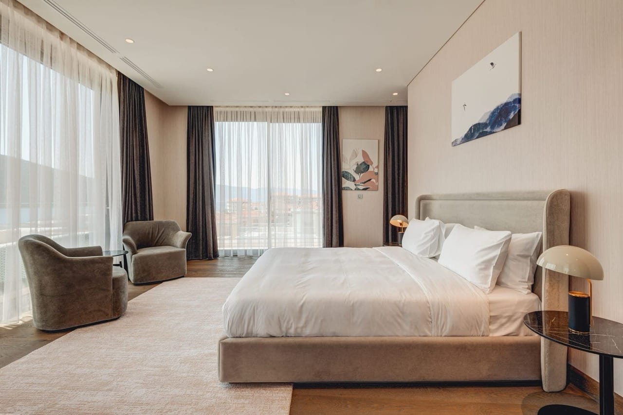 Modern bedroom in an apartment in Portonovi, Kumbor, Montenegro: double bed, panoramic windows, and sea view.