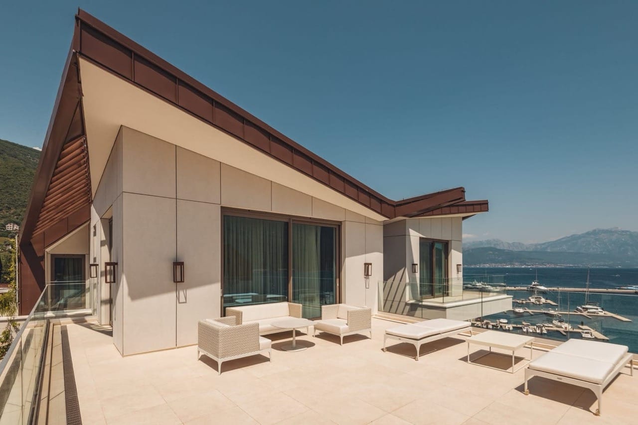 Terrace of a luxury apartment in Portonovi, Kumbor, Montenegro: wicker furniture, sun loungers, and panoramic views of the marina.