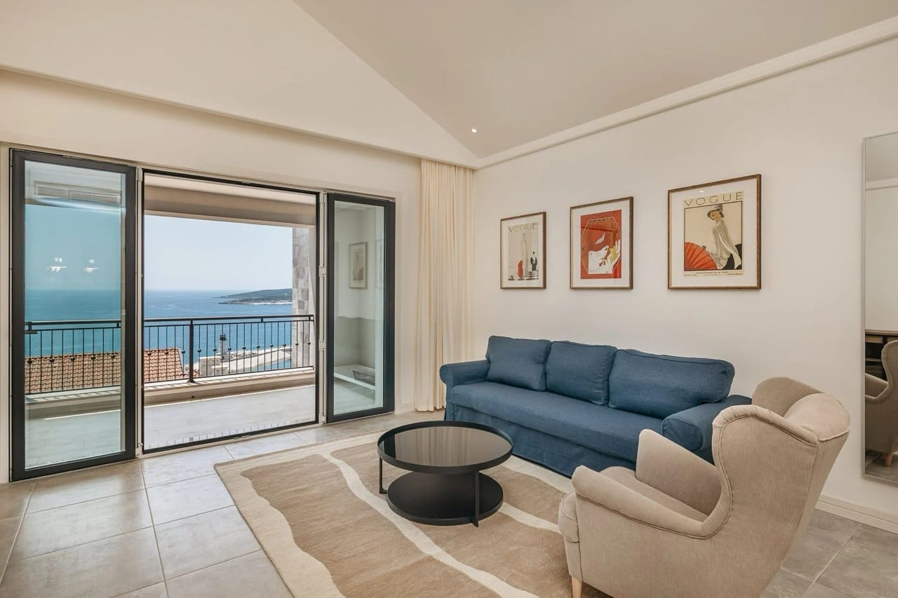 Living room in an apartment in Luštica Bay, Radovići, Montenegro: blue sofa, sea view, and a terrace with panoramic windows.