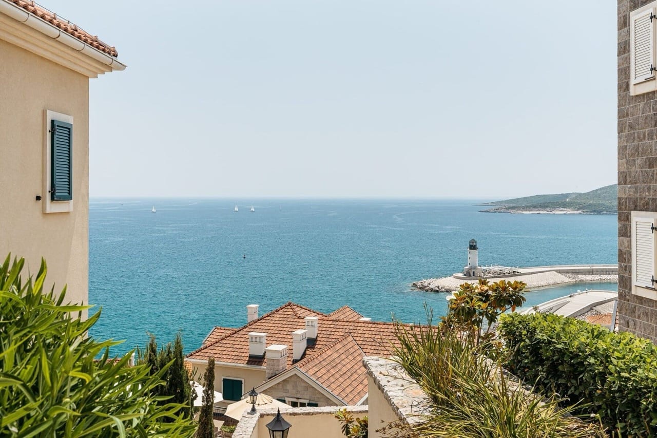 Panoramic sea view and lighthouse in Luštica Bay, Radovići, Montenegro: terrace with greenery and the complex architecture.