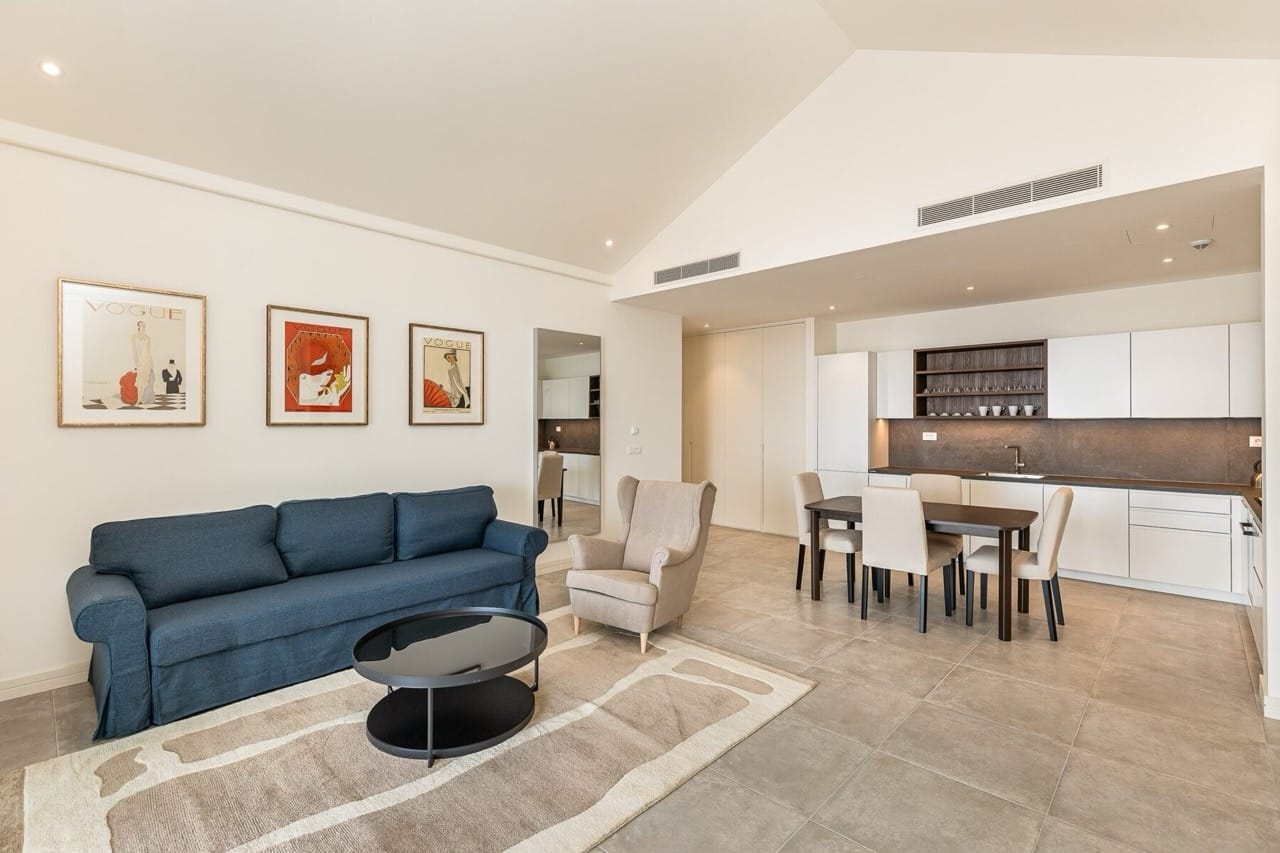 Modern living room with kitchen in Lustica Bay apartments, Radovici, Montenegro: blue sofa, dining area, and decor.