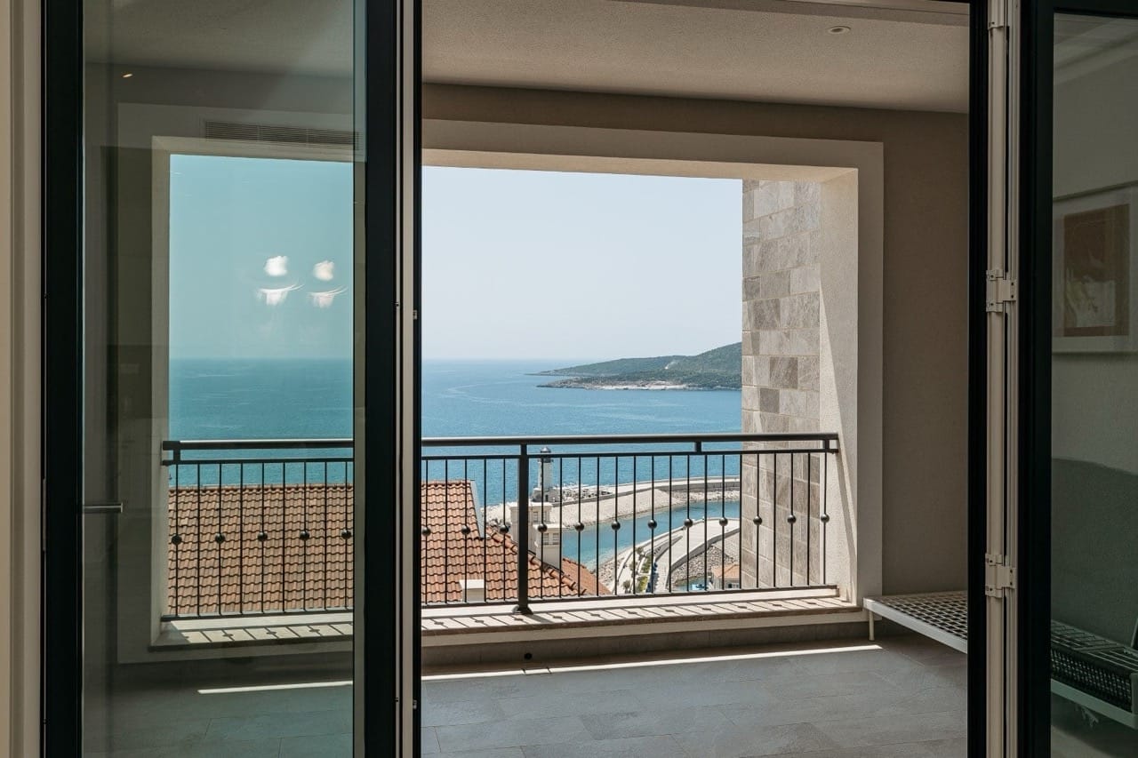 View from the apartment balcony in Luštica Bay, Radovići, Montenegro: a panorama of the sea, the marina, and terracotta roofs.
