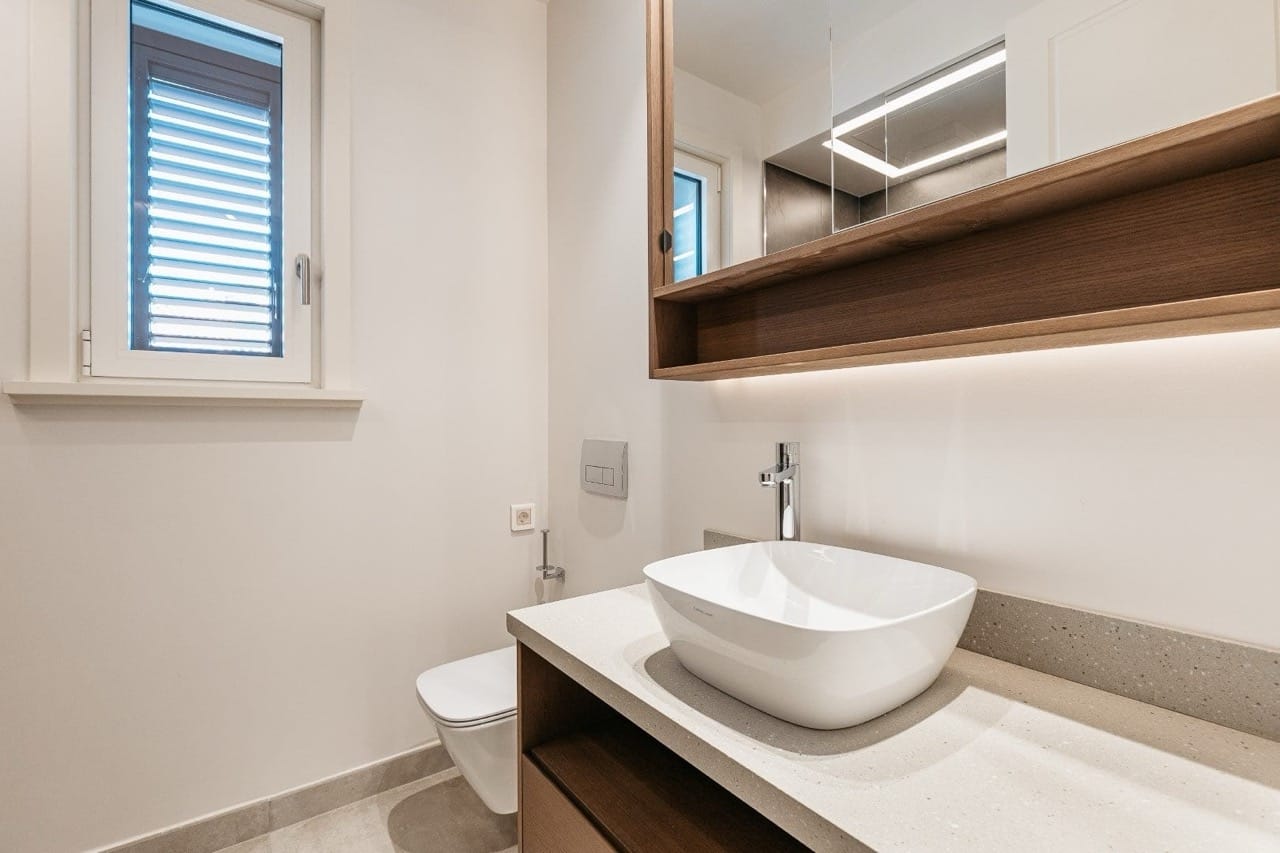 Modern bathroom in an apartment in Luštica Bay, Radovići, Montenegro: a countertop sink and a backlit mirror.