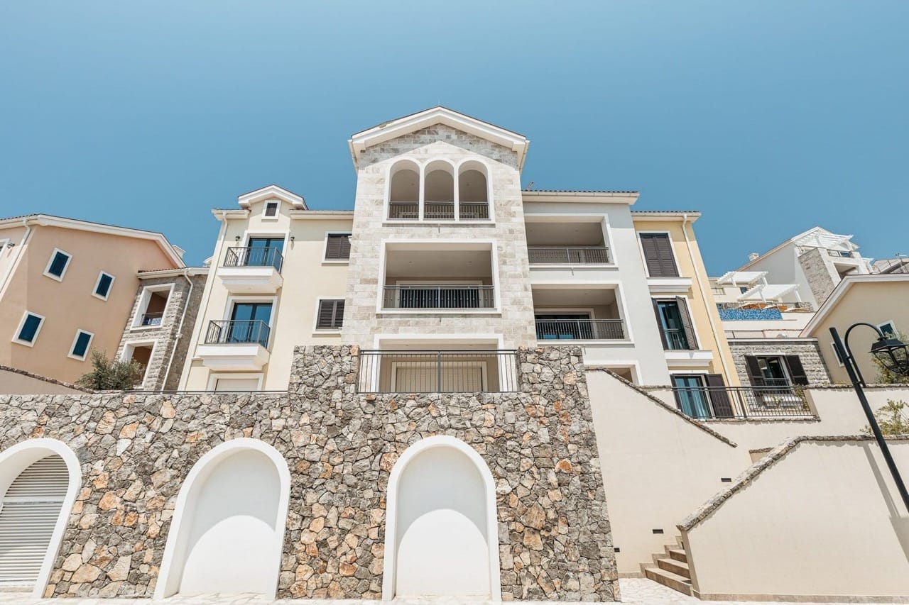 Facade of a luxury residential complex in Luštica Bay, Radovići, Montenegro: stone cladding and terraces with sea views.