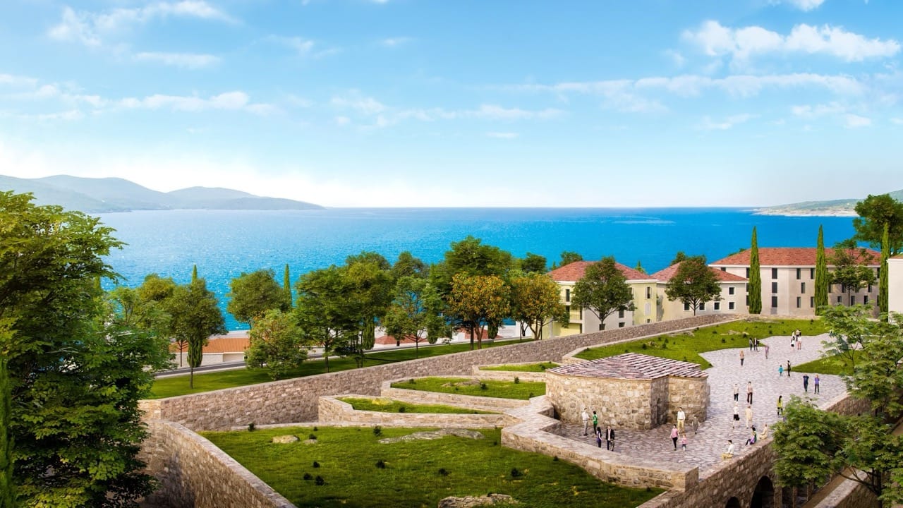 Вид на жилой комплекс Lustica Bay в Радовичи, Черногория: каменная архитектура, ухоженные газоны и морской пейзаж.