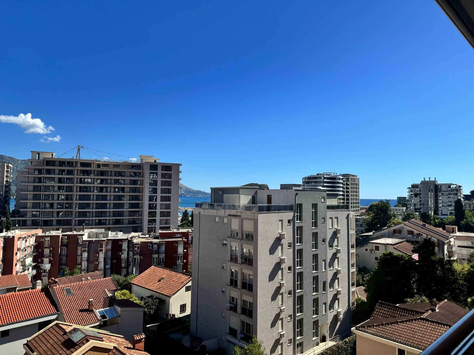 Pogled s balkona stana u Budvi, Crna Gora: panorama grada sa savremenom gradnjom i morskim horizontom.