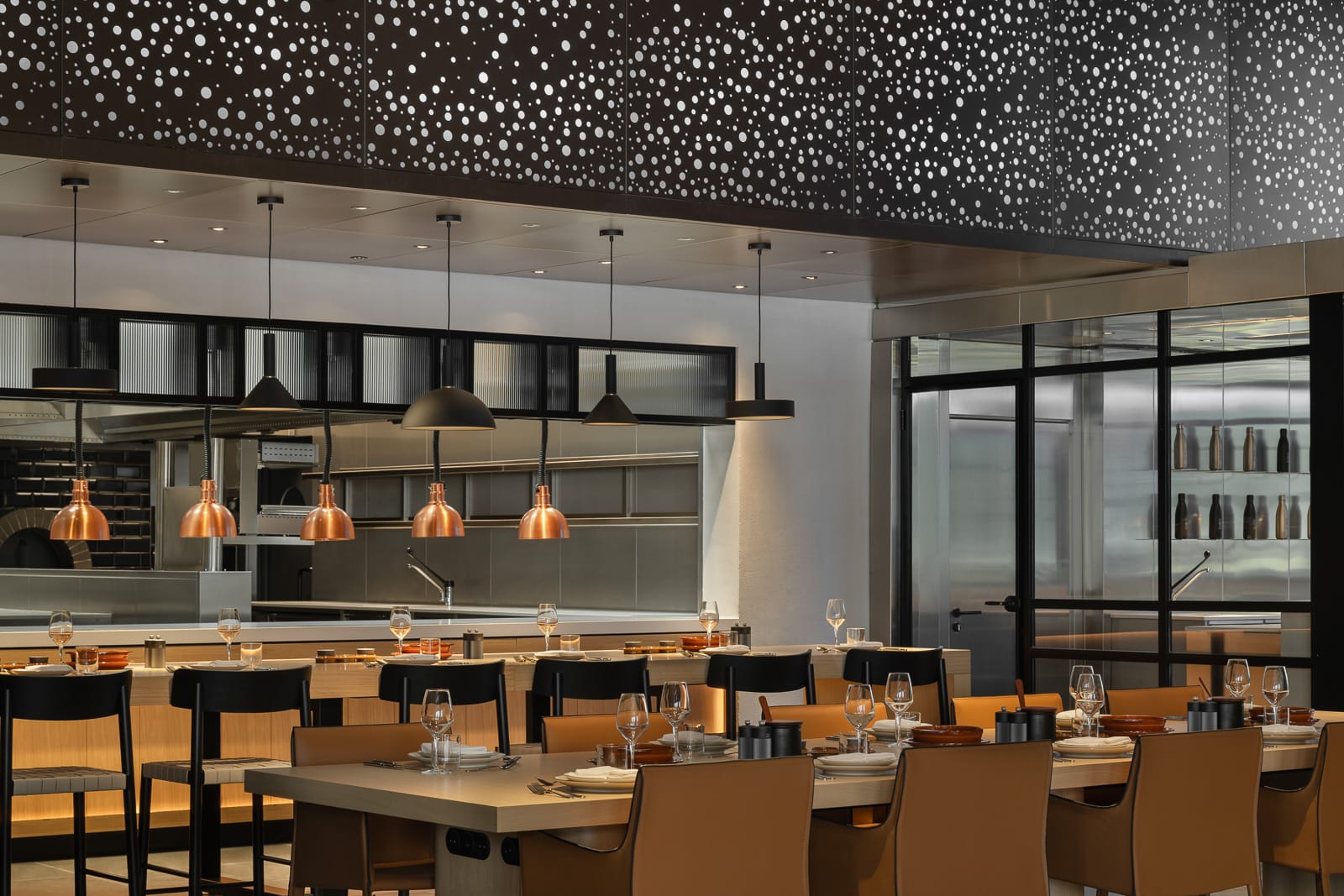 Moderan enterijer restorana u Porto Montenegru, Tivat, Crna Gora: stilni nameštaj, bakarne lampe i otvorena kuhinja.