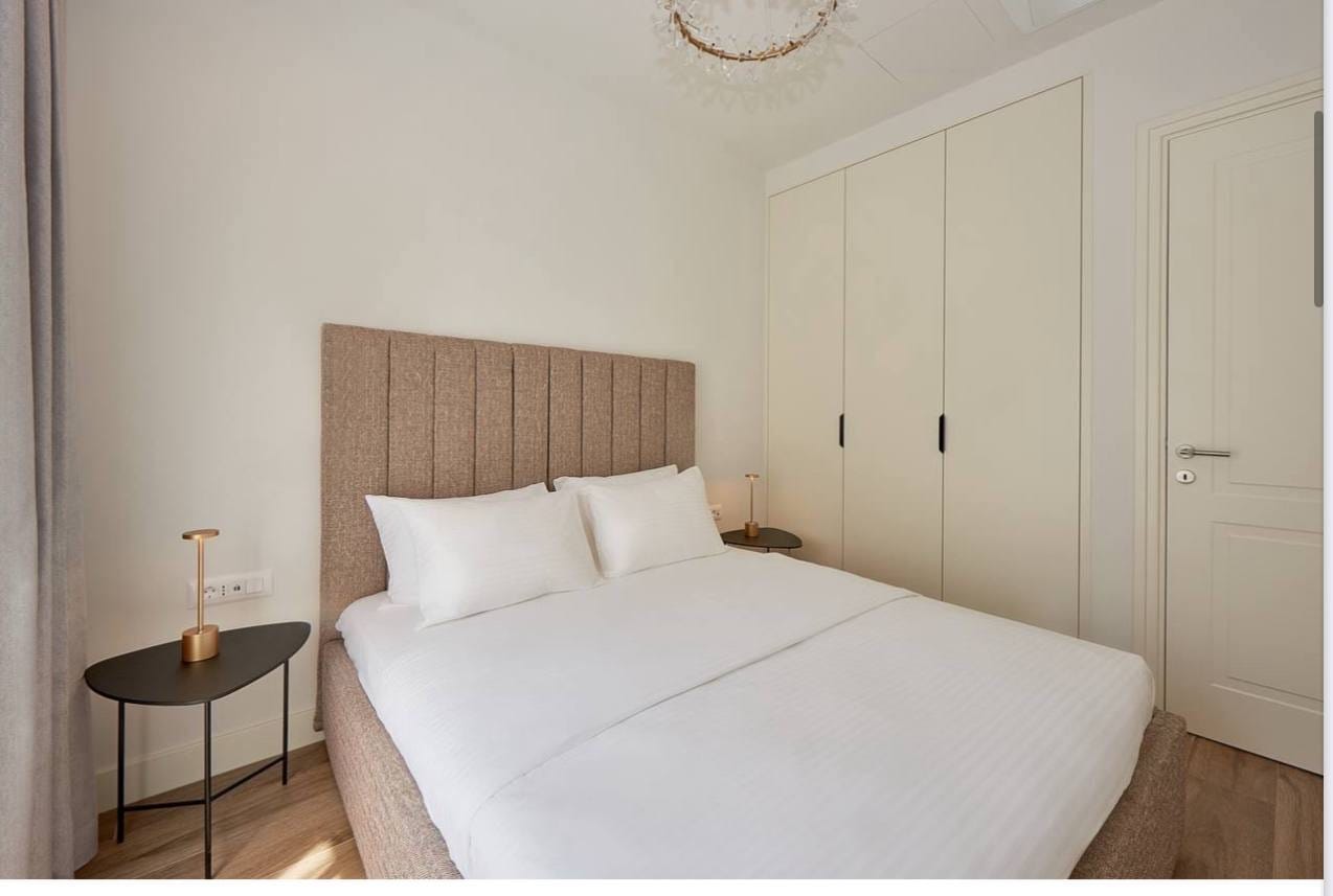 Svetla spavaća soba sa bračnim krevetom i ugradnim ormarom u apartmanima Lustica Bay, Luštica, Crna Gora.