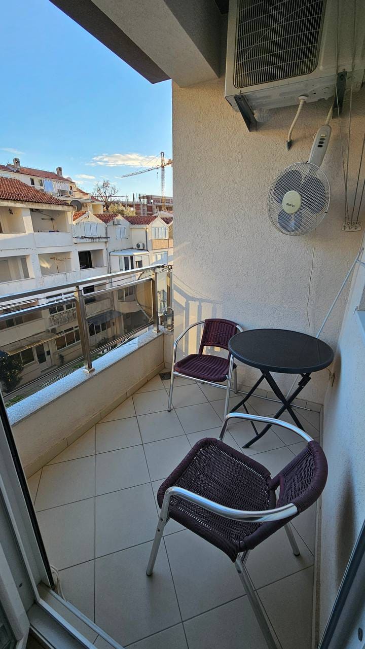 Ugodan balkon s nameštajem u stanu u Bečićima, Crna Gora: pogled na grad i stambeni kompleks, pločice na podu.