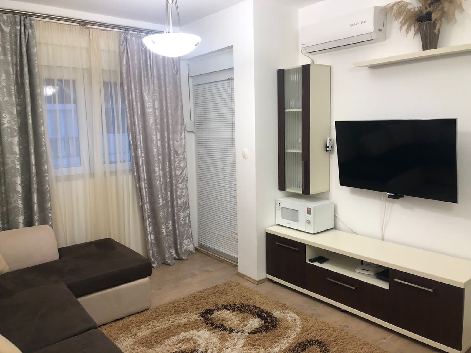 Udoban dnevni boravak u stanu u Bečićima, Crna Gora: ugaona garnitura, TV zona, klima-uređaj i svetao enterijer.