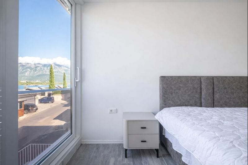 Savremena spavaća soba u townhouseu, Đuraševići, Crna Gora: panoramski prozor s pogledom na planine i more, stilisan nameštaj.