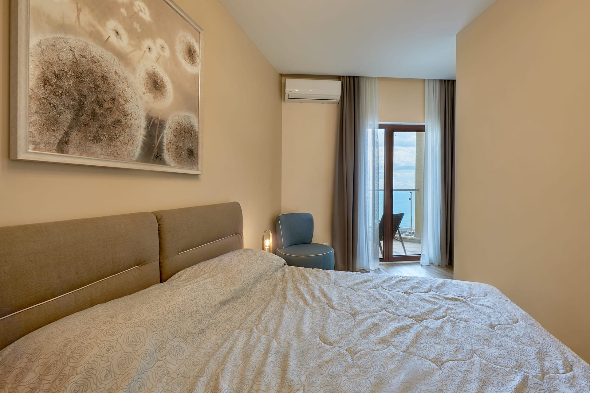 Chambre dans un appartement à Bečići, Monténégro : lit double, fauteuil et accès au balcon avec vue sur la mer.