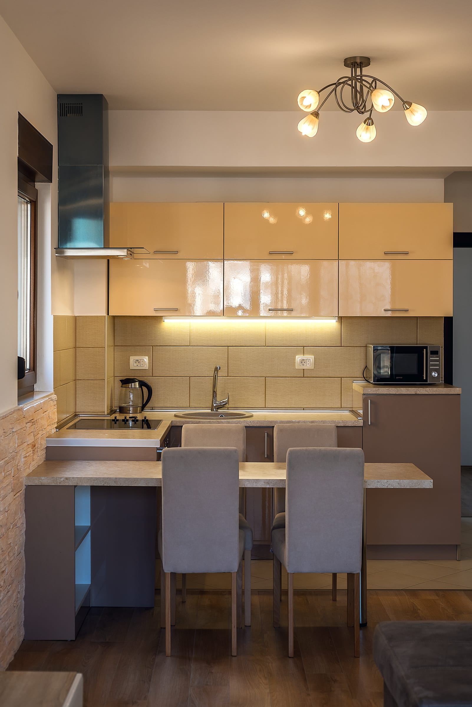 Moderna kuhinja u apartmanima Budve, Crna Gora: bež kuhinjski element, trpezarijska zona i ugrađeni uređaji.