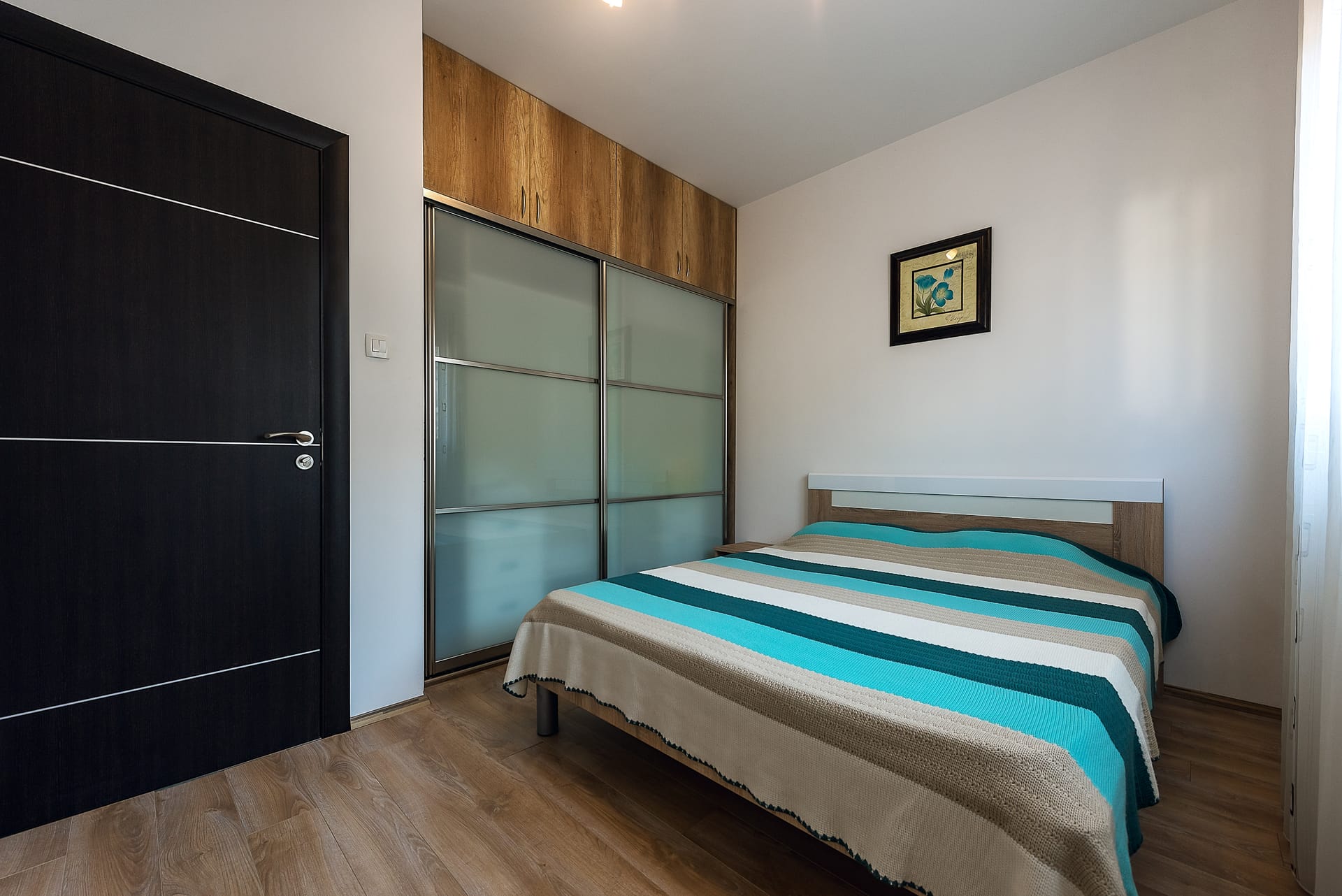Spavaća soba u apartmanima u Budvi, Crna Gora: bračni krevet, ugradbeni ormar i moderna završna obrada.