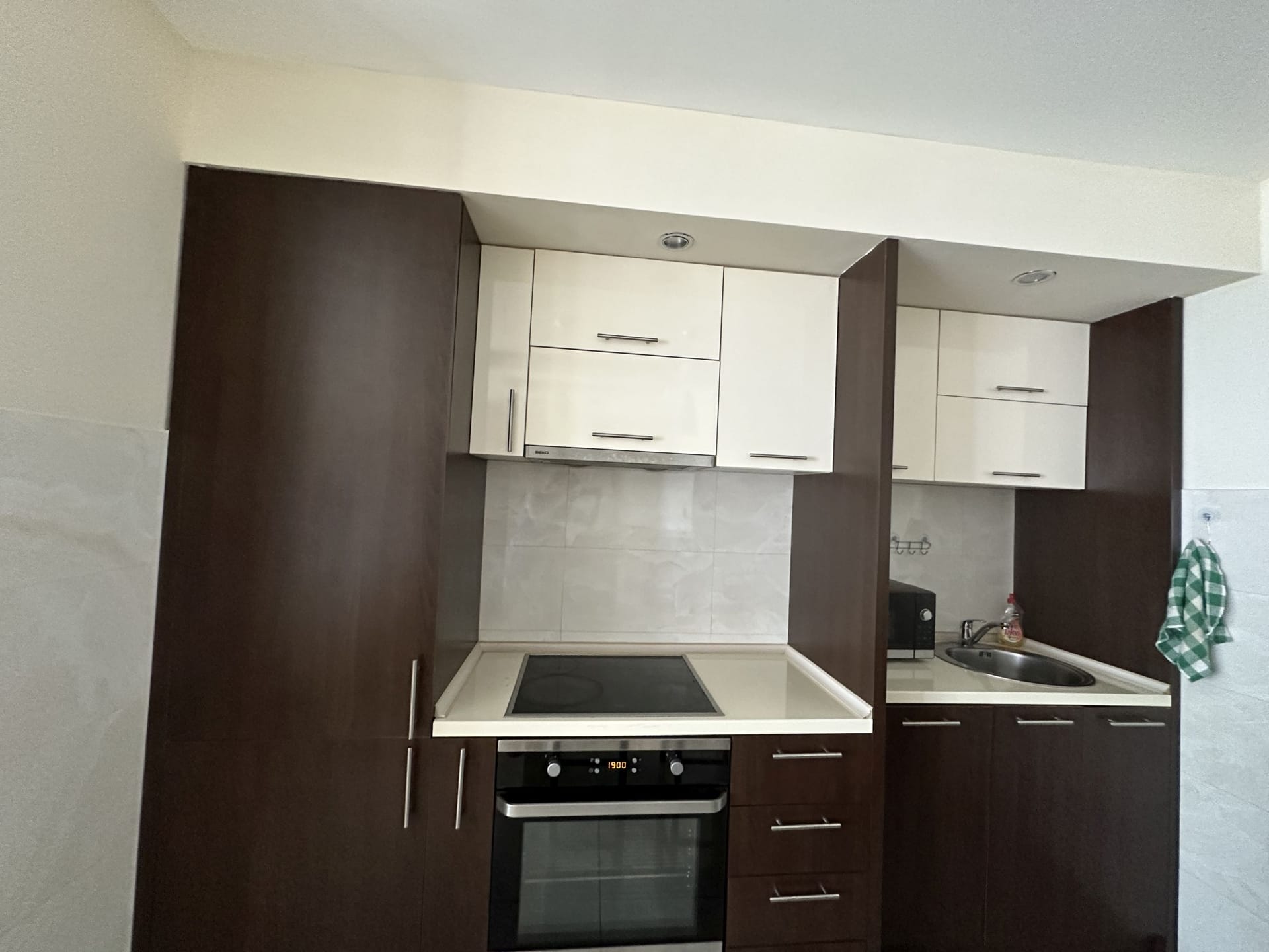 Nowoczesna kuchnia w apartamentach w Bečici, Czarnogóra: wbudowane urządzenia, ciemne fronty i jasny blat.