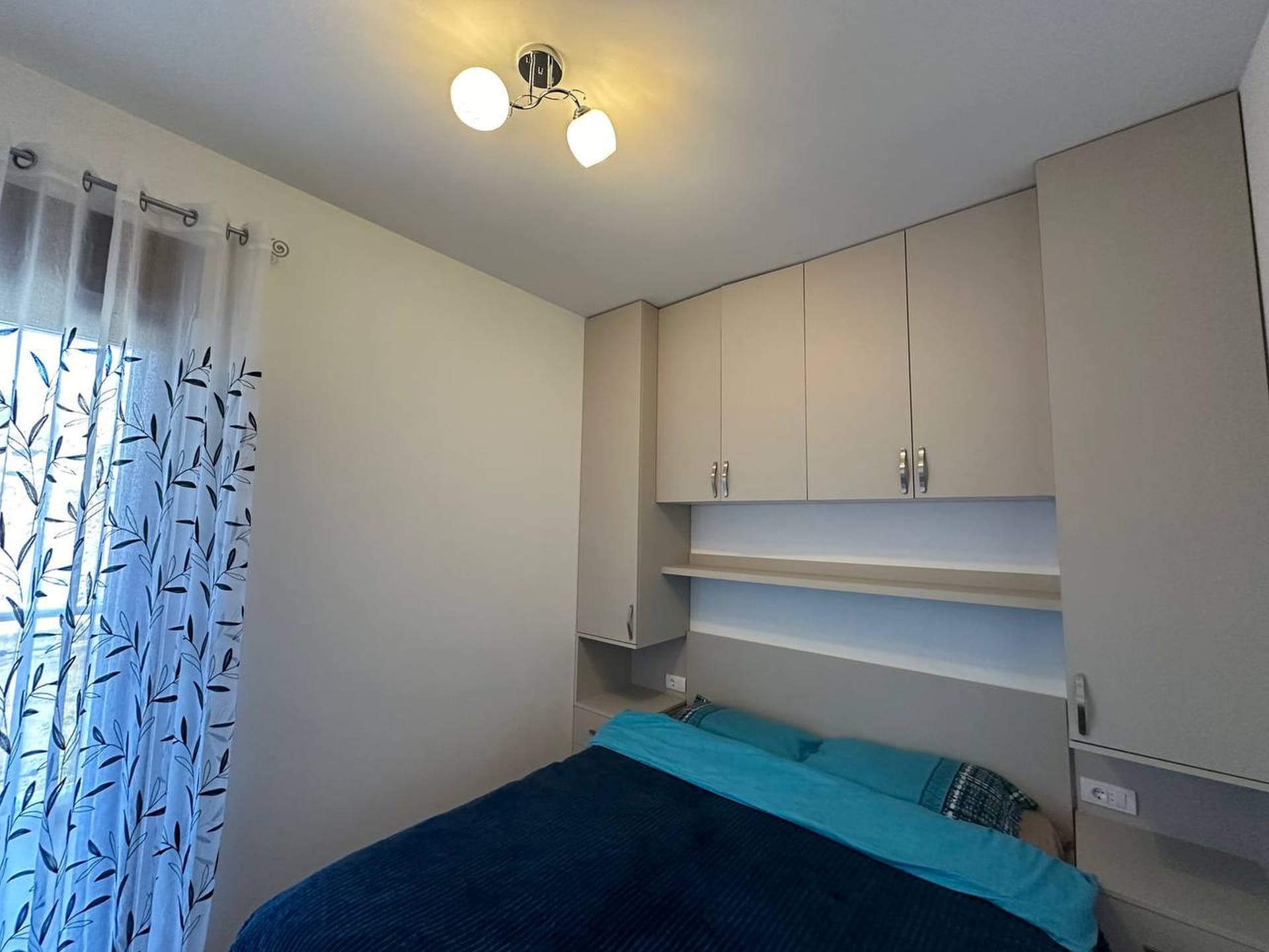 Prijatna spavaća soba u apartmanima u Bečićima, Crna Gora: bračni krevet, ugradbeni ormar i svetla završna obrada.
