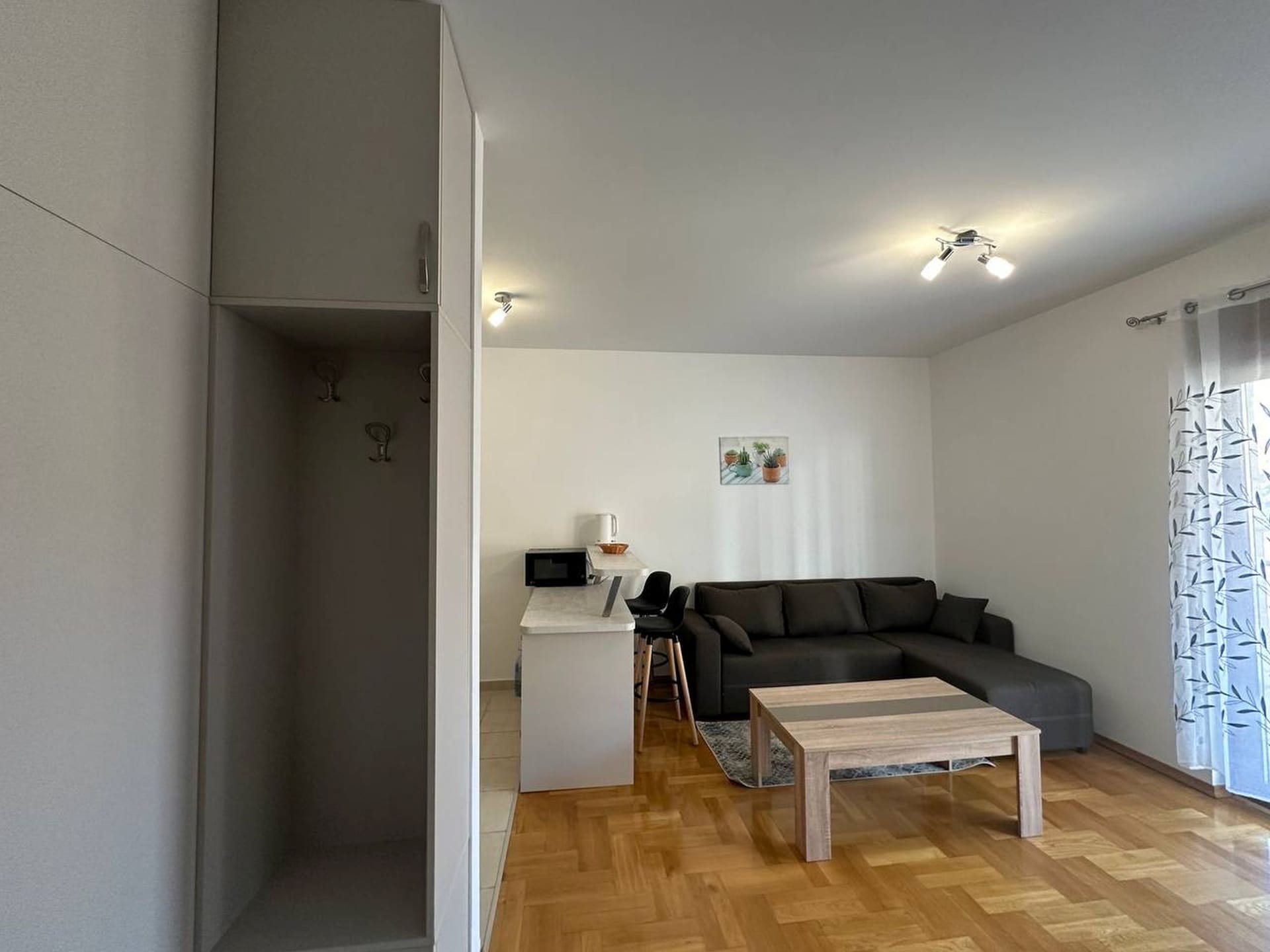 Dnevna soba sa kuhinjom i barskim pultom u apartmanima, Bečići, Crna Gora: moderan nameštaj, parket, svetli enterijer.